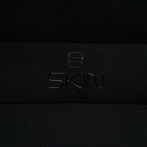 Close-up of the embossed Skin Load logo on the black padded Makeup Pouch