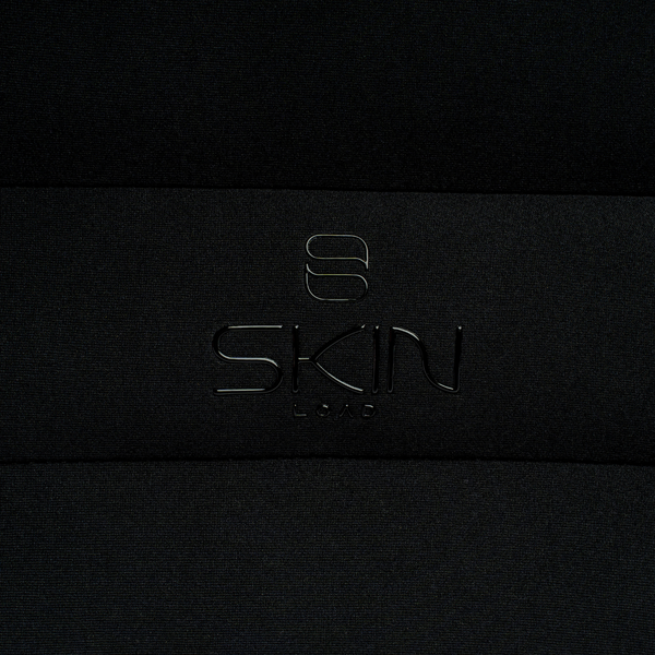 Close-up of the embossed Skin Load logo on the black padded Makeup Pouch